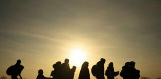 White South Africans Flock to U.S. Under Controversial Plan Silhouetted group of refugees walking towards the sunset