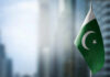 Flag of Pakistan waving in a blurred urban background
