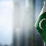 Flag of Pakistan waving in a blurred urban background