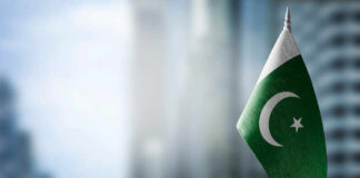 Flag of Pakistan waving in a blurred urban background