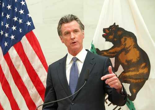 A government official delivering a speech with flags in the background
