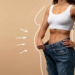 Woman showcasing weight loss by holding oversized jeans