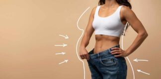 Woman showcasing weight loss by holding oversized jeans