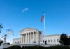 U.S. Supreme Court building with American flag and blue sky