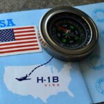 A compass placed on a travel document featuring an H-1B visa and a map of the USA