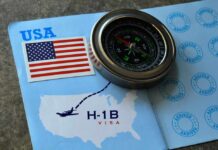 A compass placed on a travel document featuring an H-1B visa and a map of the USA