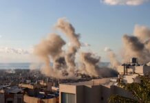 Smoke rising from buildings in a city with a coastal view