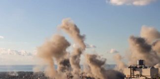 Smoke rising from buildings in a city with a coastal view