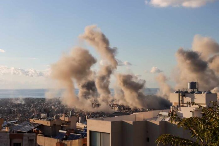 Smoke rising from buildings in a city with a coastal view