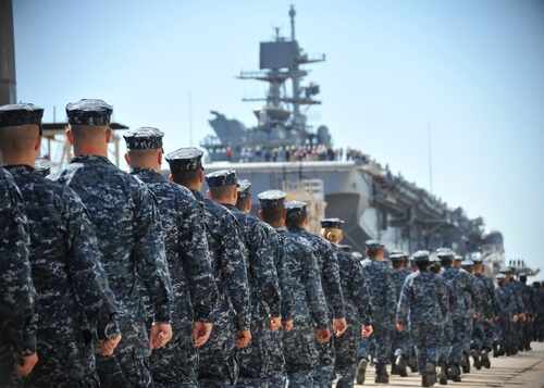 Uniformed naval personnel marching towards a ship
