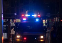 Emergency vehicle with flashing lights in a busy urban area at night