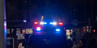 Emergency vehicle with flashing lights in a busy urban area at night