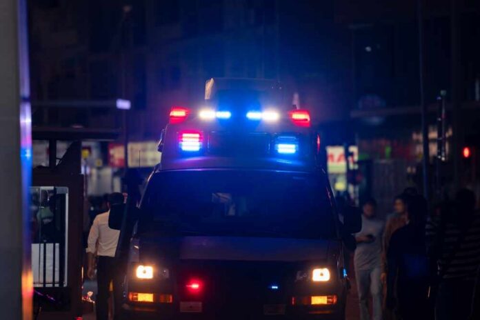 Emergency vehicle with flashing lights in a busy urban area at night