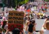 Large crowd at a protest holding signs with various messages