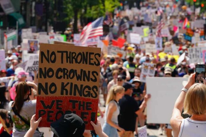 Large crowd at a protest holding signs with various messages