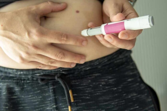 Person administering an insulin injection to their abdomen