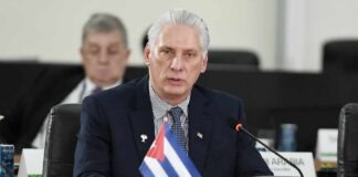 Cuban official speaking at a conference with a flag in front