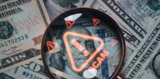 Magnifying glass over U.S. dollar bills with a scam warning
