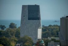 A modern building overlooking a lake with trees in the foreground