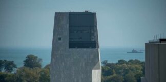 A modern building overlooking a lake with trees in the foreground