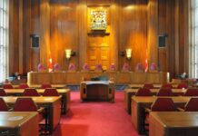 Interior view of a courtroom with wooden paneling and red seating