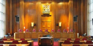 Interior view of a courtroom with wooden paneling and red seating