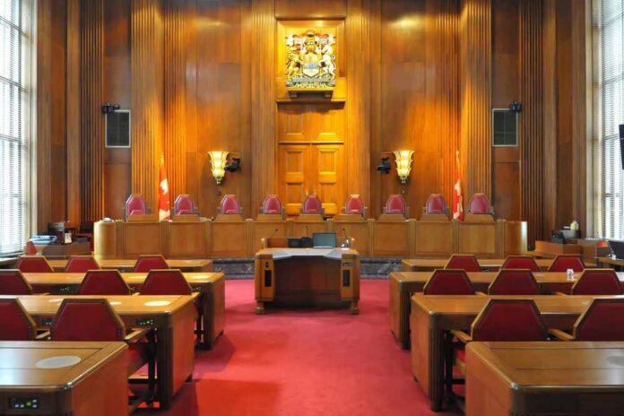 Interior view of a courtroom with wooden paneling and red seating