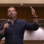 A speaker addressing an audience with a microphone in hand