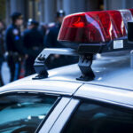 Close-up of a police car with red lights and officers in the background