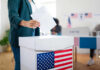 A person casting a vote into a ballot box at a polling station