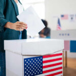 A person casting a vote into a ballot box at a polling station