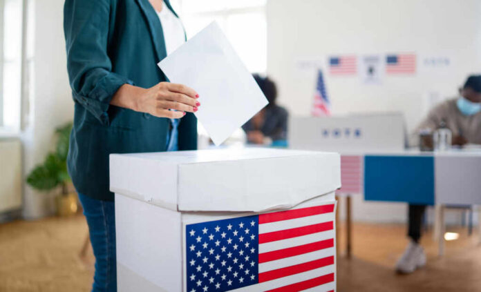 A person casting a vote into a ballot box at a polling station