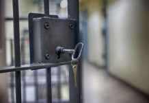 Close-up of a locked jail cell door with a key inserted