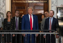 A group of individuals, including a political figure, standing in front of a courtroom entrance