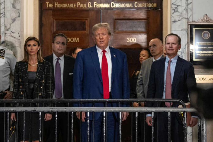 A group of individuals, including a political figure, standing in front of a courtroom entrance