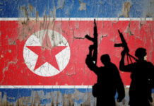 Silhouettes of armed figures in front of a distressed North Korean flag