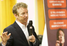 A man in a suit speaking into a microphone during a presentation