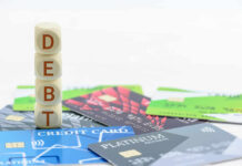 Stack of wooden blocks spelling DEBT on top of various credit cards