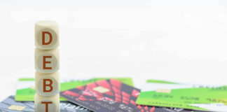 Debt Trap: High Earners Struggle to Stay Afloat Stack of wooden blocks spelling DEBT on top of various credit cards
