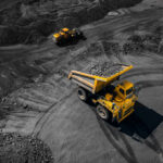 A large yellow dump truck loaded with rocks on a mining site