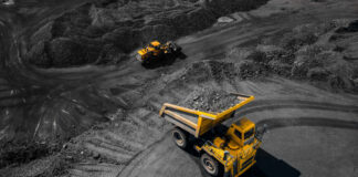 A large yellow dump truck loaded with rocks on a mining site