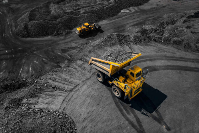 A large yellow dump truck loaded with rocks on a mining site