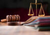 A wooden gavel and scales of justice on a table with law books