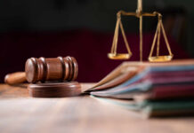 A wooden gavel and scales of justice on a table with law books