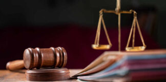 A wooden gavel and scales of justice on a table with law books