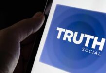 Close-up of a hand holding a smartphone displaying the Truth Social app logo