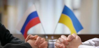 Clasped hands of two individuals with Russian and Ukrainian flags in the background