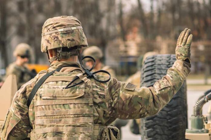 A soldier in camouflage uniform saluting with one hand raised
