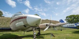 Vintage aircraft parked on a grassy field under a blue sky