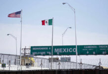 Flags of the United States and Mexico at a border crossing with a welcome sign